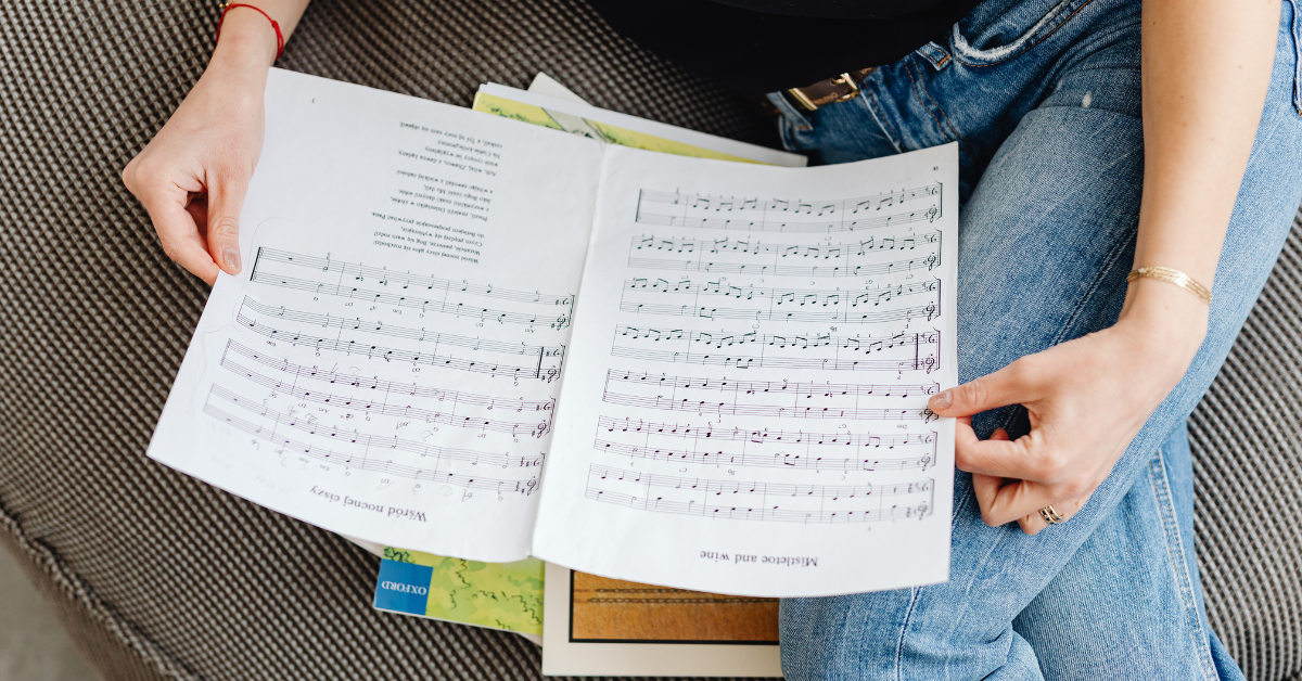 Persona seduta che consulta uno spartito musicale sopra un divano