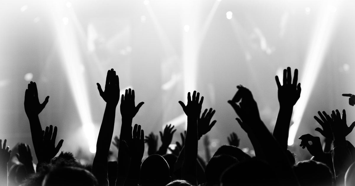 Pubblico a un concerto con mani alzate e luci di scena