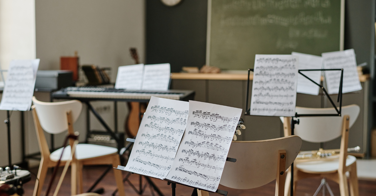 Aula con sedie, leggii e spartiti musicali, ambiente didattico dedicato alla formazione musicale di gruppi e classi.